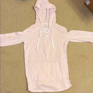 Pink hoodie with cross strings, pocket in front.